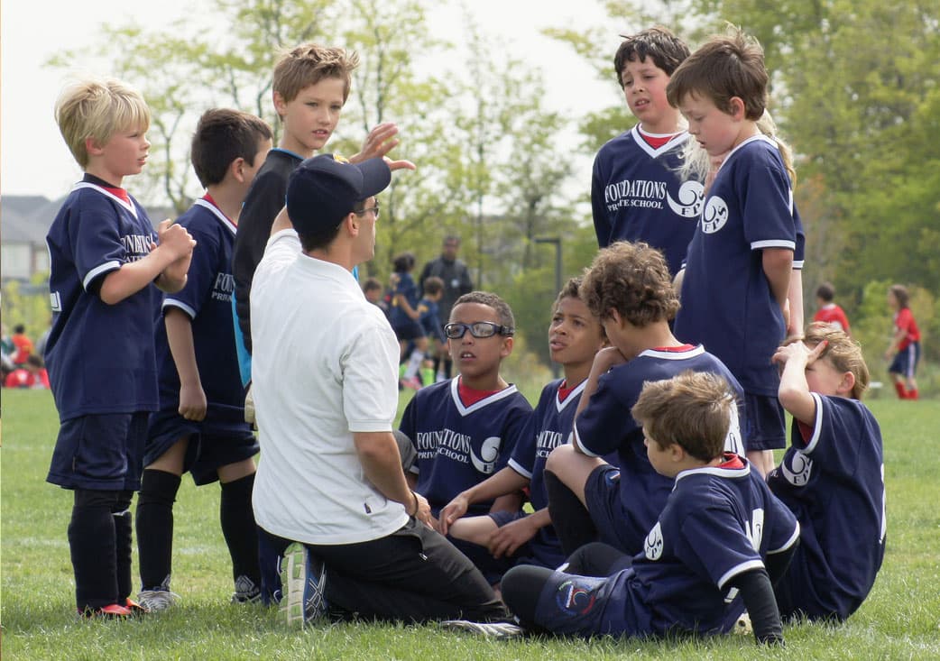 Coach gathering with youth soccer team on the field