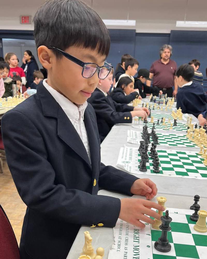 Student focused at a chess tournament in navy blazer